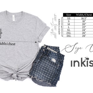 Pu&ograve; includere: Una maglietta unisex per adulti Bella Canvas grigio chiaro con una tabella delle taglie. La maglietta &egrave; abbinata a pantaloncini di jeans e scarpe da ginnastica Converse bianche. La tabella delle taglie mostra le misure in cm per larghezza/petto e lunghezza.