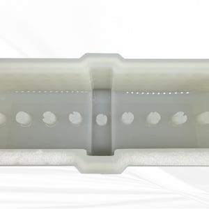 Op de afbeelding: Een close-up van een doorschijnende, gebroken witte plastic container. De container heeft een rechthoekige vorm met een reeks cirkelvormige uitsparingen langs de onderrand. Het ontwerp omvat een verhoogd middengedeelte en een getextureerde basis.