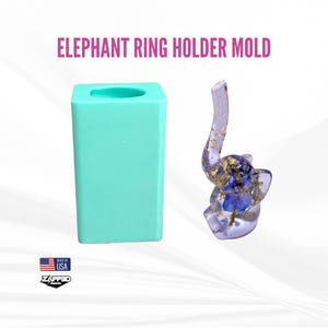 May include: A light blue silicone mold shaped like an elephant with a ring holder. The mold is next to a clear resin elephant ring holder with gold leaf and blue flowers.