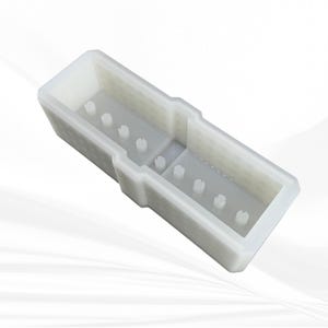 Op de afbeelding: Een witte, rechthoekige siliconen mal met interne verdelers en kleine, cilindrische pinnen. De mal heeft een getextureerd uiterlijk en is ontworpen voor het maken van ambachten. De algemene vorm is een lange, open container.
