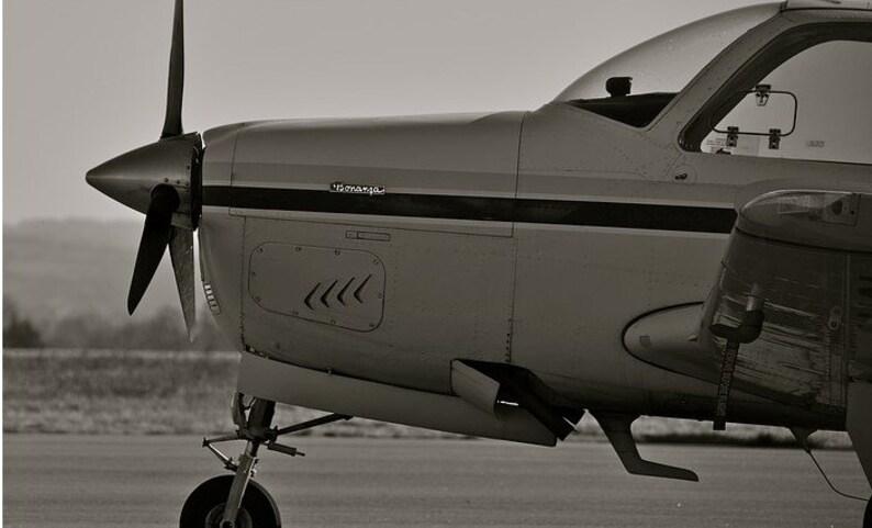 May include: A black and white photo of a small, single-engine airplane with a propeller. The plane is on the ground and the word "remarkable" is visible on the side of the plane.