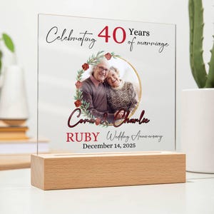 May include: A clear acrylic block with a wooden base, featuring a photo of a couple and text that reads "Celebrating 40 Years of marriage." The names "Cora & Charlie" are displayed, along with "Ruby Wedding Anniversary" and the date "December 14, 2025."