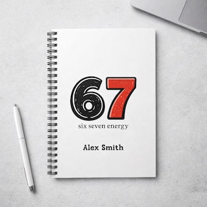 May include: White spiral-bound notebook with the number "67" in black and red on the cover. The text "six seven energy" and "Alex Smith" are below the numbers. A white pen is on the left.