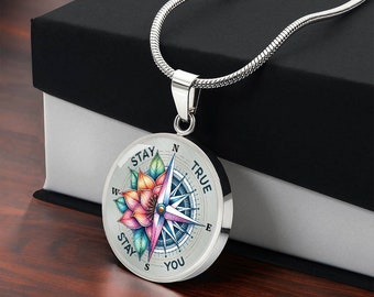 May include: Silver necklace with a compass pendant featuring a colorful flower design and the words "Stay True Stay You".