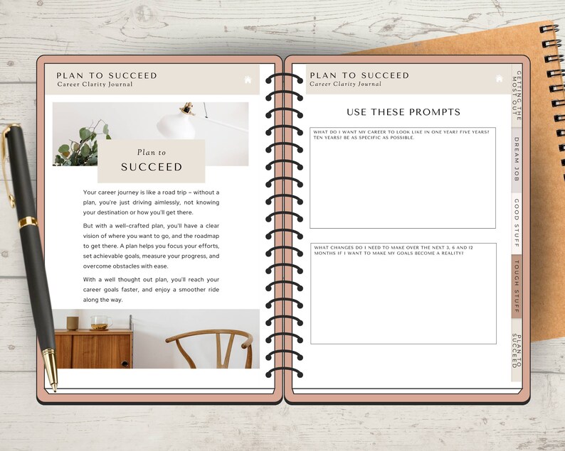 May include: A pink and brown journal with the title "Plan to Succeed: Career Clarity Journal" on the cover. The journal has a spiral binding and is open to a page with the text "Plan to Succeed" and prompts for career planning.