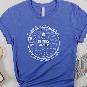 May include: A royal blue t-shirt featuring a white circle graphic that reads "Cycle 2 Memory Master" and includes icons representing various school subjects. The text surrounding the circle says "To Know God and Make Him Known".