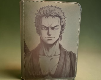 May include: A rectangular trading card binder with a textured grey surface featuring a detailed monochromatic illustration of the anime character Roronoa Zoro. The character has short spiky hair, a scar over one eye, and wears a robe. The word Vault X is embossed.
