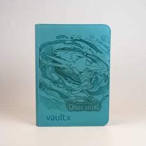 May include: A teal-colored trading card binder featuring a dark teal graphic illustration of a stylized creature and swirling patterns. The text "MEGA EVOLUTION CHAOS RISING" is printed in the center, with the "vaultx" logo at the bottom left corner.