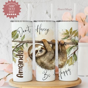 May include: Three white stainless steel tumblers with a watercolor sloth design. The tumblers have the text "Don't Hurry Be Happy" and "Amanda" on them.