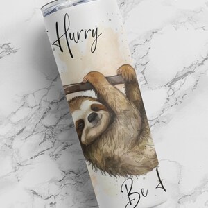 May include: White stainless steel tumbler with a sloth hanging from a branch. The tumbler has the text "Hurry Be 4" printed on it.