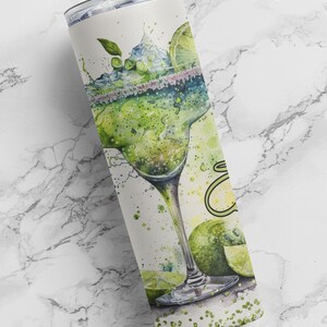 May include: A stainless steel tumbler with a watercolor design of a margarita glass with lime slices and green glitter.