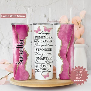 May include: A pink and gold tumbler with a quote that reads "always remember you are braver than you believe, stronger than you seem, smarter than you think, and loved more than you know". The tumbler has a butterfly design and the name "Samantha" is written on the side.