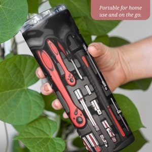 Op de afbeelding: Een zwarte en rode 20 ounce roestvrijstalen tumbler met een ontwerp van gereedschap in een gereedschapskist. De tekst "20 oz. Size Tumbler. Portable for home use and on the go." is op de tumbler gedrukt.