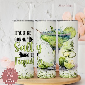 May include: A white tumbler with a green glitter design and the text "If you're gonna be salty bring the tequila". The tumbler is next to a similar tumbler with a watercolor illustration of a margarita glass and lime slices. The text "Olivia" is on the tumbler.