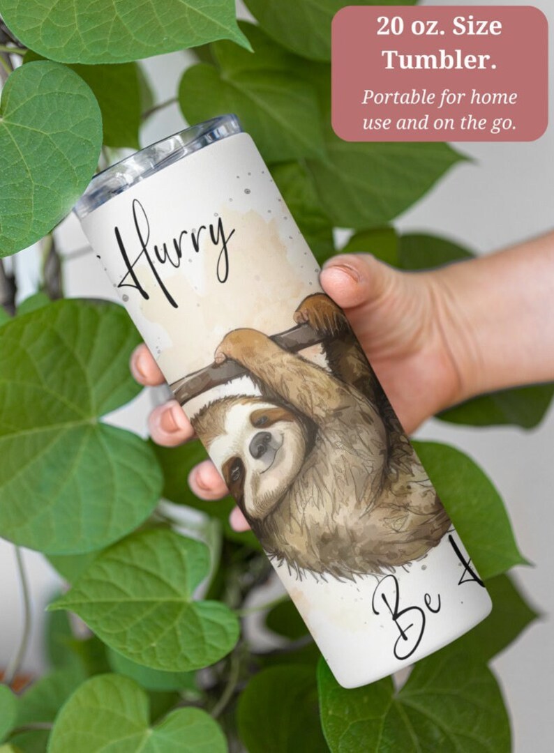 May include: A white 20 ounce stainless steel tumbler with a watercolor illustration of a sloth hanging from a branch. The tumbler has the text "Hurry" at the top and "Be" at the bottom.
