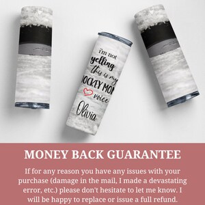May include: A white and gray tumbler with a black and white image of a hockey rink. The tumbler has the text "I'm not yelling this is my hockey mom voice Olivia" printed on it.