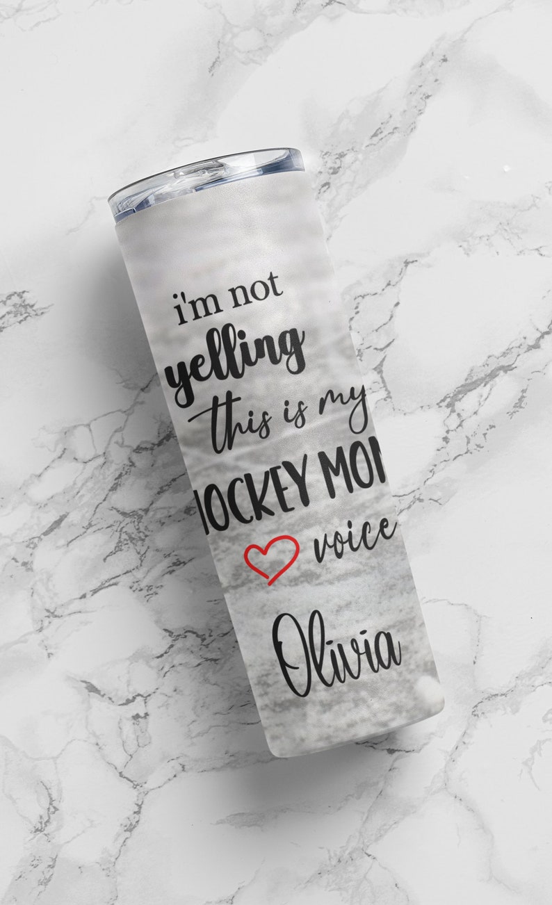 May include: White tumbler with a black and red design that says "I'm not yelling this is my hockey mom voice Olivia".