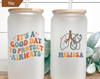 May include: Two frosted glass tumblers with bamboo lids and straws. One tumbler has the text "IT'S A GOOD DAY TO PROTECT AIRWAYS" in colorful retro lettering. The other has a lung graphic, stethoscope, and the name "MELISSA". Each tumbler holds 16oz.