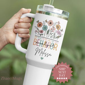 May include: White tumbler with a handle, featuring a floral design with butterflies and the text "IT'S OKAY TO FEEL ALL THE FEELS BEHAVIOR Analyst Melissa". The tumbler has a clear lid and a straw.