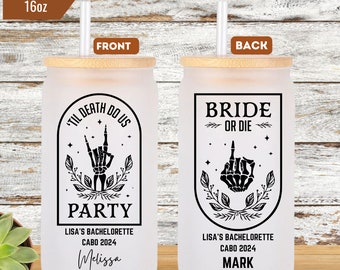 May include: Two 16 ounce frosted glass tumblers with bamboo lids and straws. The front tumbler has a black and white graphic of a skeleton hand with the text "Til Death Do Us Party" and "Lisa's Bachelorette Cabo 2024 Melissa". The back tumbler has a black and white graphic of a skeleton hand with the text "Bride or Die" and "Lisa's Bachelorette Cabo 2024 Mark".