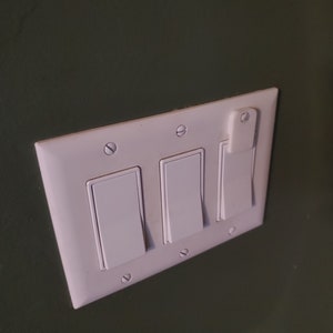 May include: A white light switch plate with three toggle switches. The switches are all in the off position.