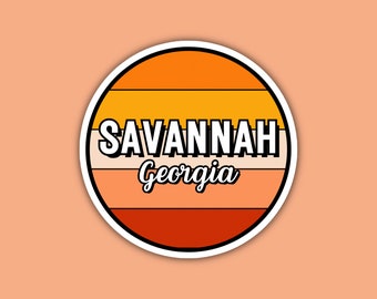 May include: A round sticker with a retro design featuring orange, yellow, and red stripes. The sticker says "SAVANNAH Georgia" in white text.