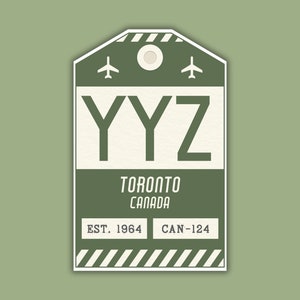 May include: Green luggage tag with white text that reads "YYZ Toronto Canada EST. 1964 CAN-124". Two small airplane icons are above the text "YYZ".