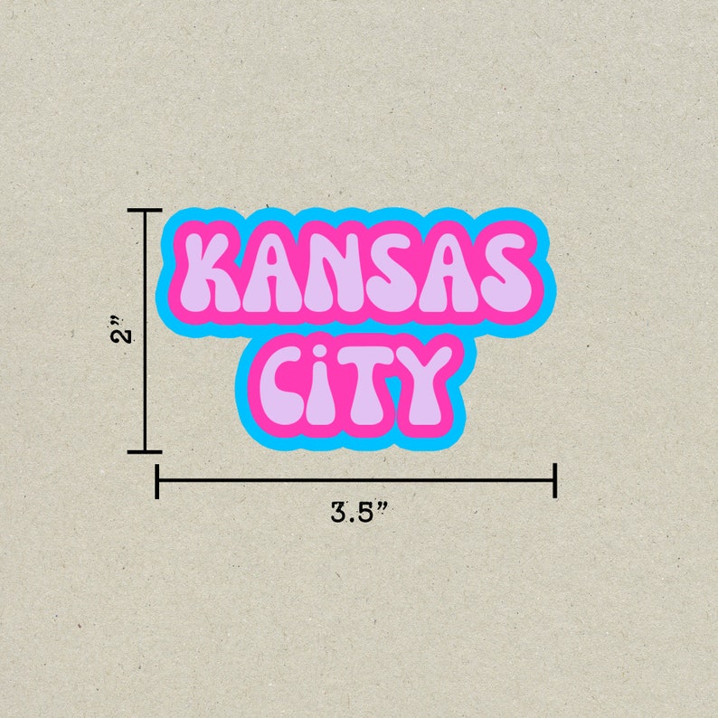 May include: A pink and blue sticker with the text "KANSAS CITY" in a retro font style. The sticker is 3.5 inches wide and 2 inches tall.