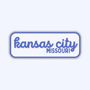 May include: A rectangular sticker with rounded corners, featuring the words "kansas city" in blue cursive script above "MISSOURI" in a smaller, sans-serif font. The text is set against a white background with a blue border.