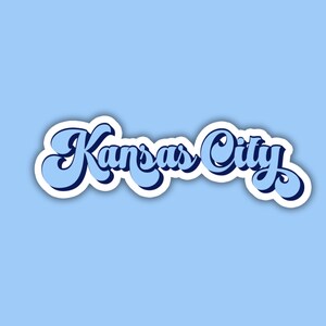 K&ouml;nnte beinhalten: Ein blauer und wei&szlig;er Aufkleber mit dem Text "Kansas City" in einer Retro-Schrift.