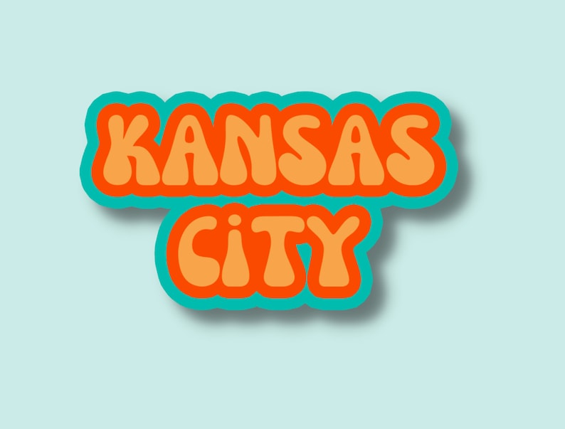 May include: A retro-style graphic with the text "KANSAS CITY" in orange letters with a teal outline. The letters are stylized with rounded edges and a slight shadow effect.