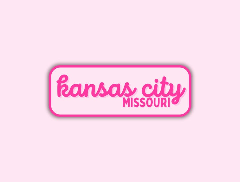 May include: A rectangular sticker with rounded corners, featuring the words "kansas city MISSOURI" in a vibrant pink script font. The text is set against a white background with a pink border, all on a light pink backdrop.