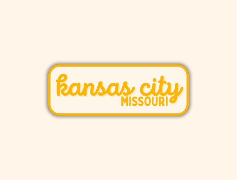 May include: A rectangular sticker with rounded corners. The sticker has a cream-colored background with a yellow border. The words "kansas city" are written in yellow cursive script above the word "MISSOURI" in a smaller, blocky yellow font.