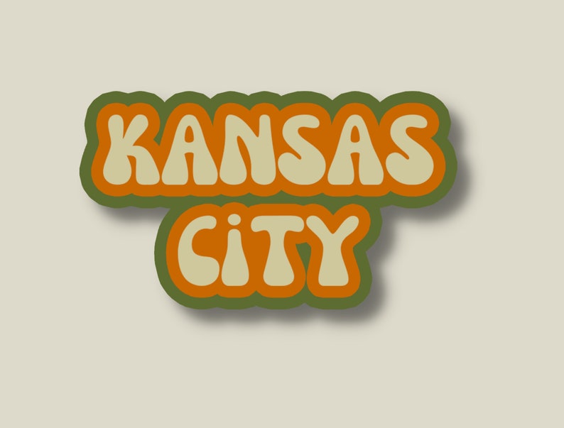 May include: A retro-style sticker with the text "KANSAS CITY" in orange and beige letters with a green outline.