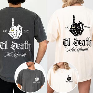 May include: Two t-shirts, one charcoal gray and one cream, feature a skeleton hand giving the middle finger, with a ring. The text reads "Til Death" and "Mr. Smith" or "Mrs. Smith", with "est. 2023".