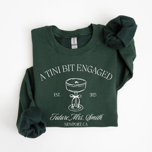 A dark green sweatshirt with white text and graphics printed on it.