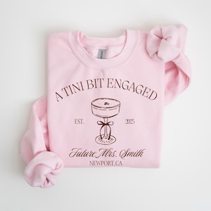 A pink sweatshirt with text and a graphic design on it.