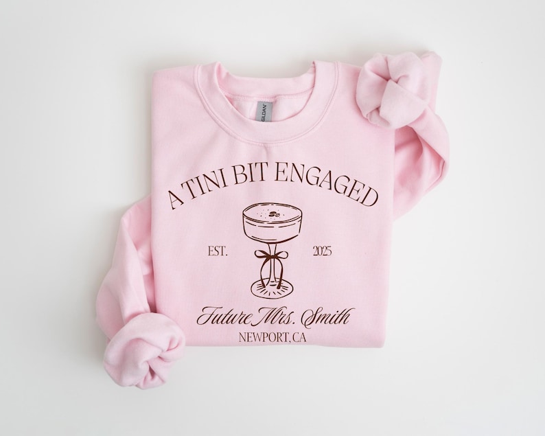 A pink sweatshirt with text and a graphic design on it.