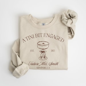 A beige sweatshirt with a graphic design and text printed on it.