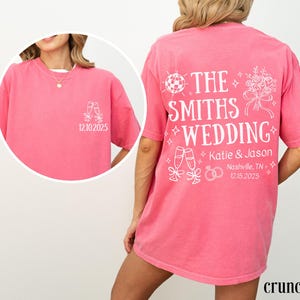 A woman wearing a pink t-shirt with white text and graphics on the back.