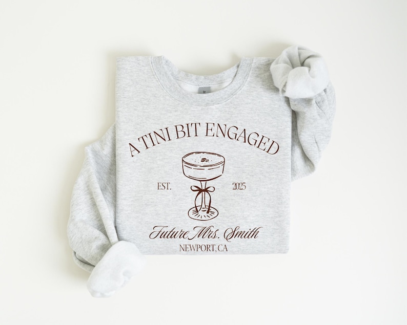 A gray sweatshirt with a graphic design and text printed on it.