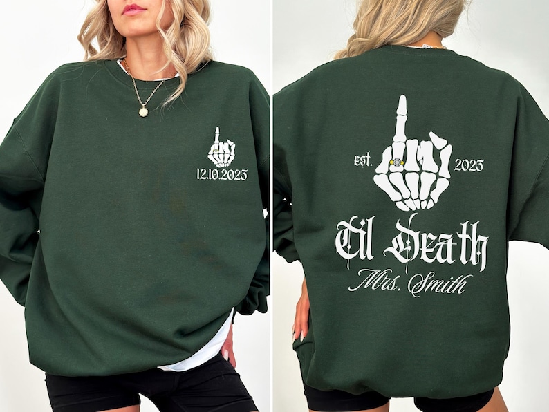 A woman wearing a green sweatshirt with white text and graphics on the back.