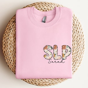a pink shirt with the word slp spread on it