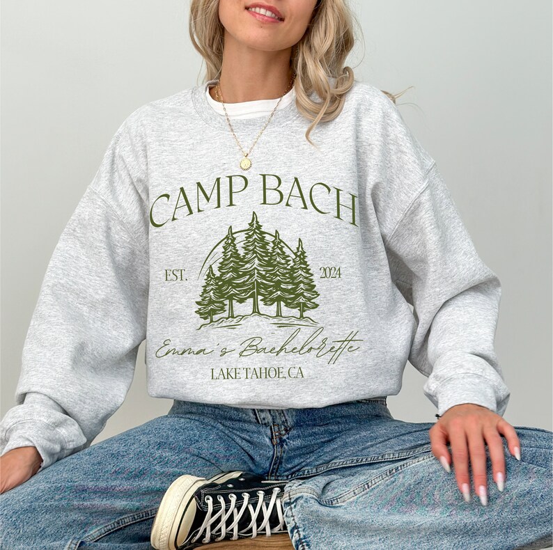a woman sitting on a stool wearing a sweatshirt