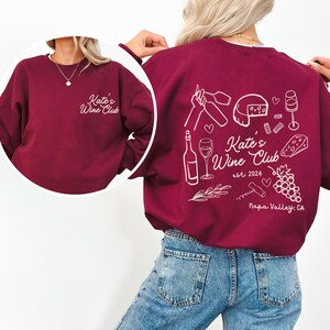 a woman wearing a red sweatshirt and jeans