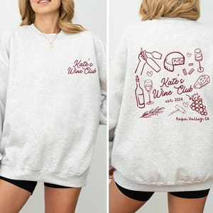 a woman wearing a sweatshirt with wine related items on it
