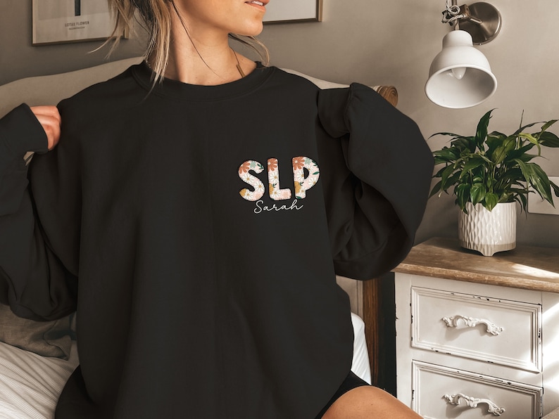 a woman sitting on a bed wearing a black sweatshirt