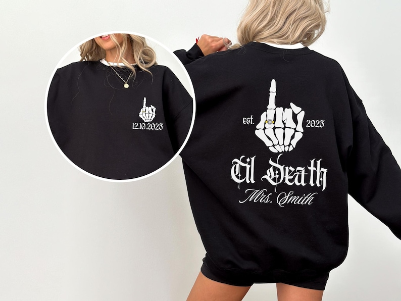 A woman wearing a black sweatshirt with white text and graphics on the back.