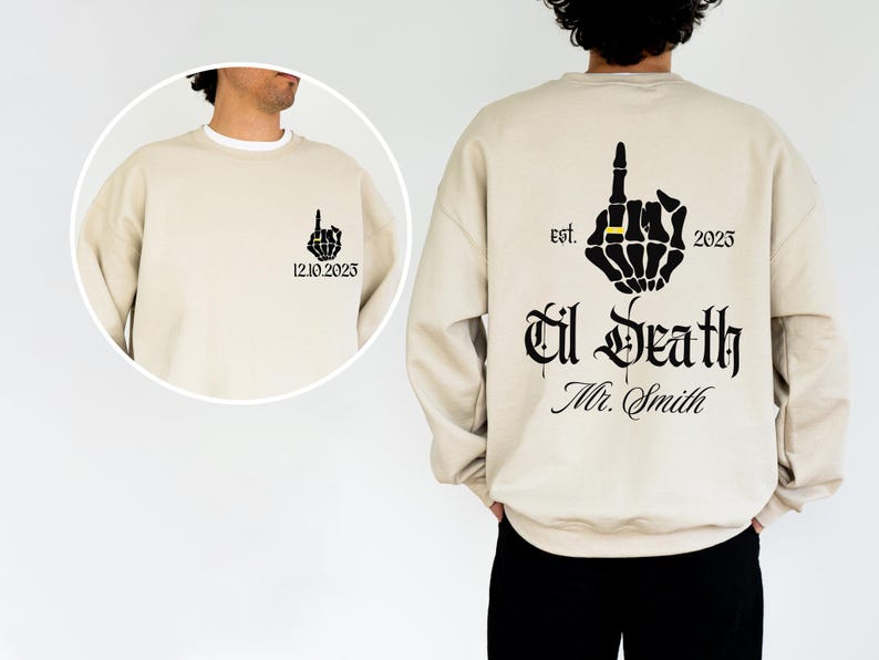 A man wearing a beige sweater with a graphic design on the back.