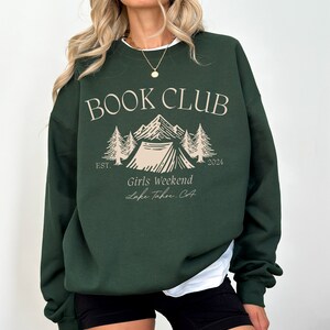 a woman wearing a green book club sweatshirt